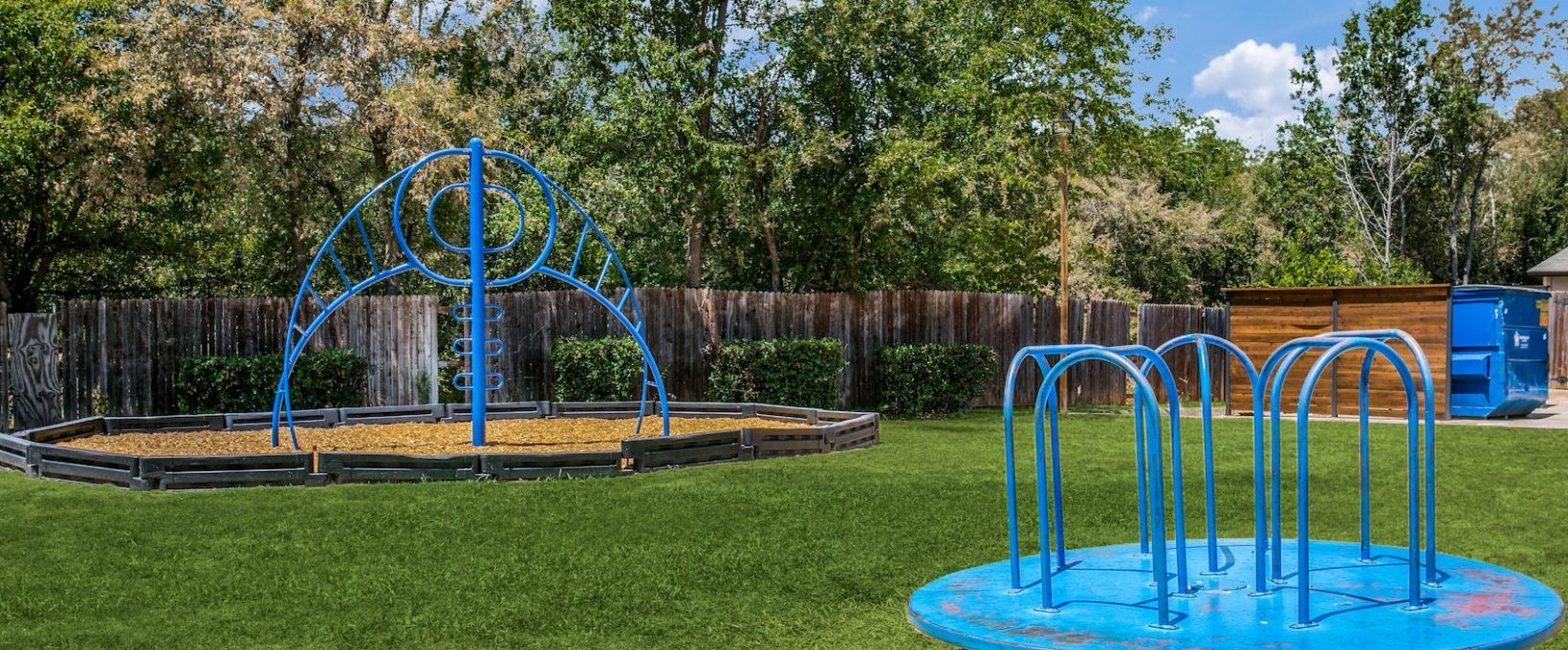 a playground with a blue slide and blue water fountain at The 8500 Harwood