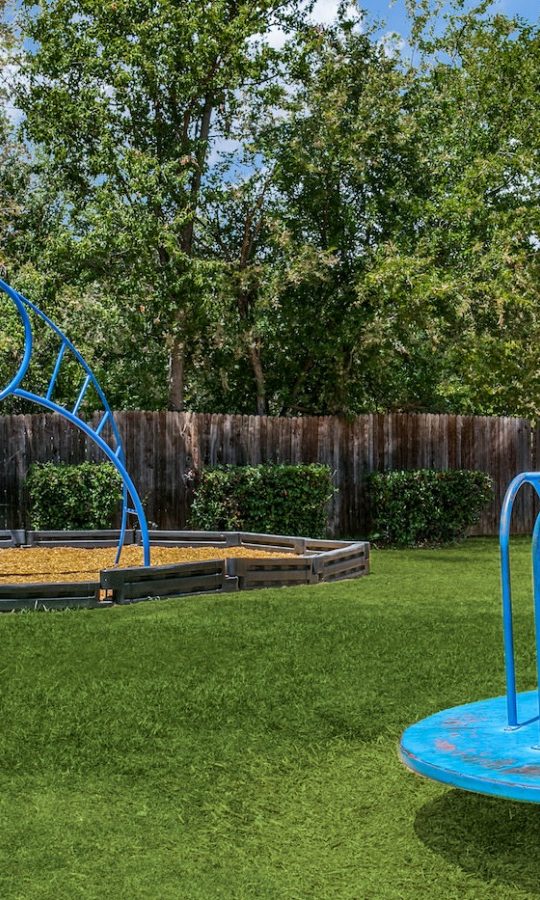 a playground with a blue slide and blue water fountain at The 8500 Harwood